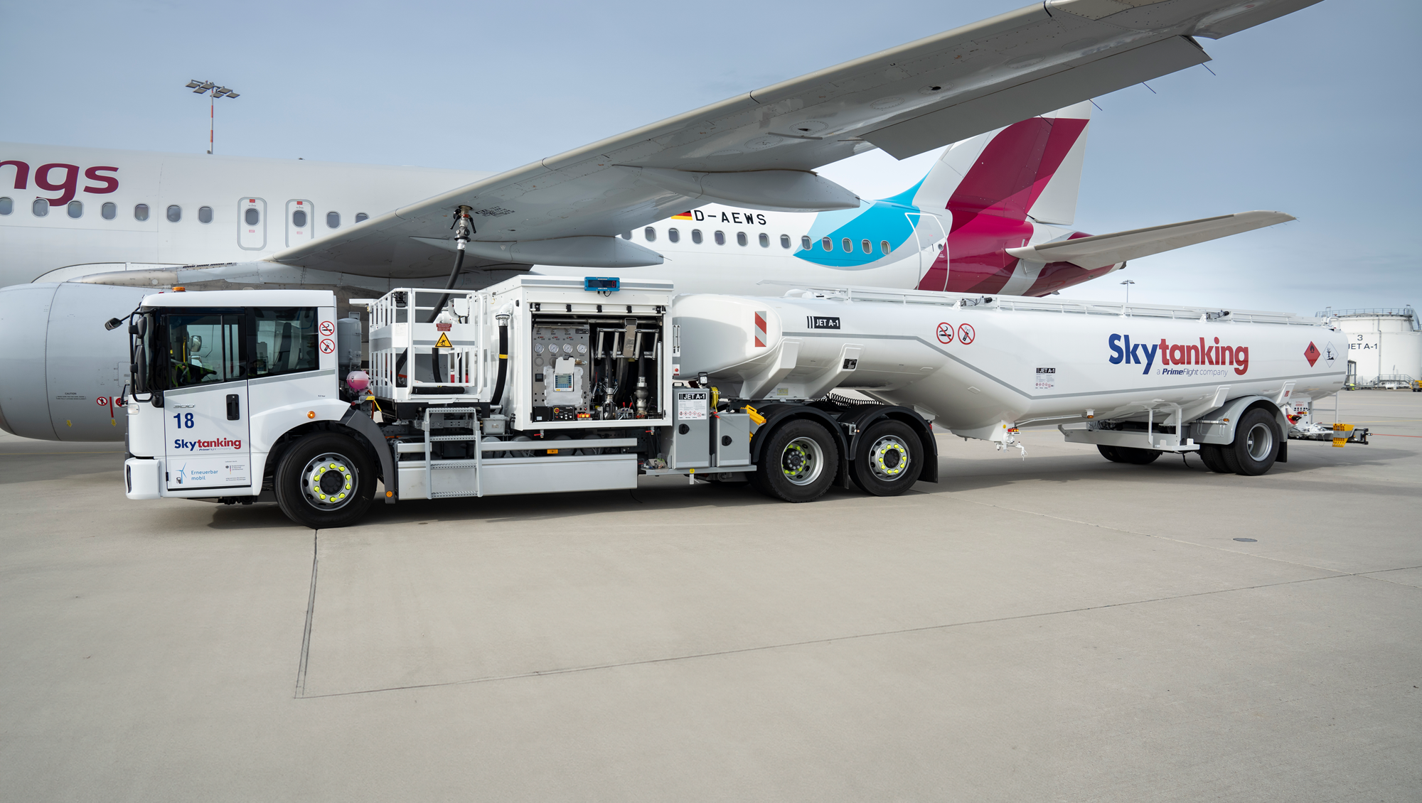 Ein elektrischer Flugzeugtankwagen der Firma Skytanking betankt ein parkendes Flugzeug.